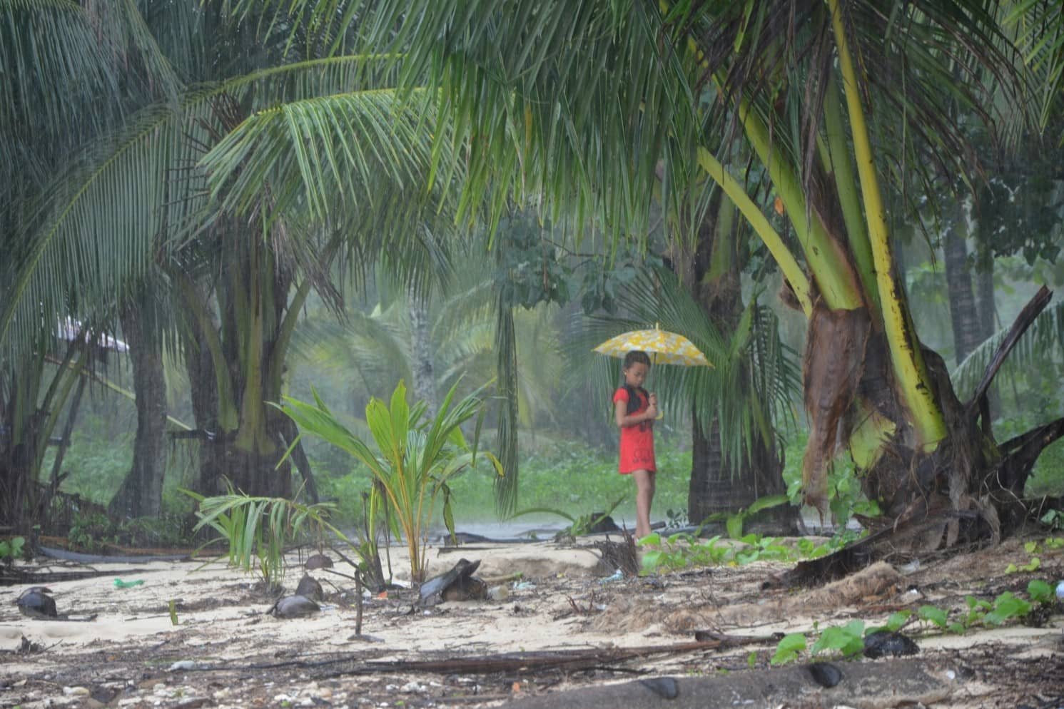 a child with an umbrella sheltering themselves on a rainy day in siargao